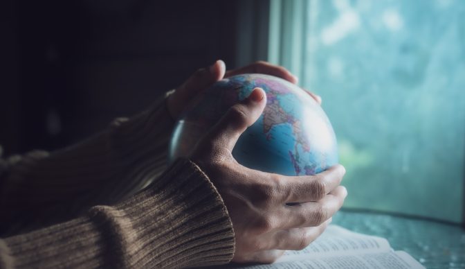 Man holding the globe and praying for people around the world.